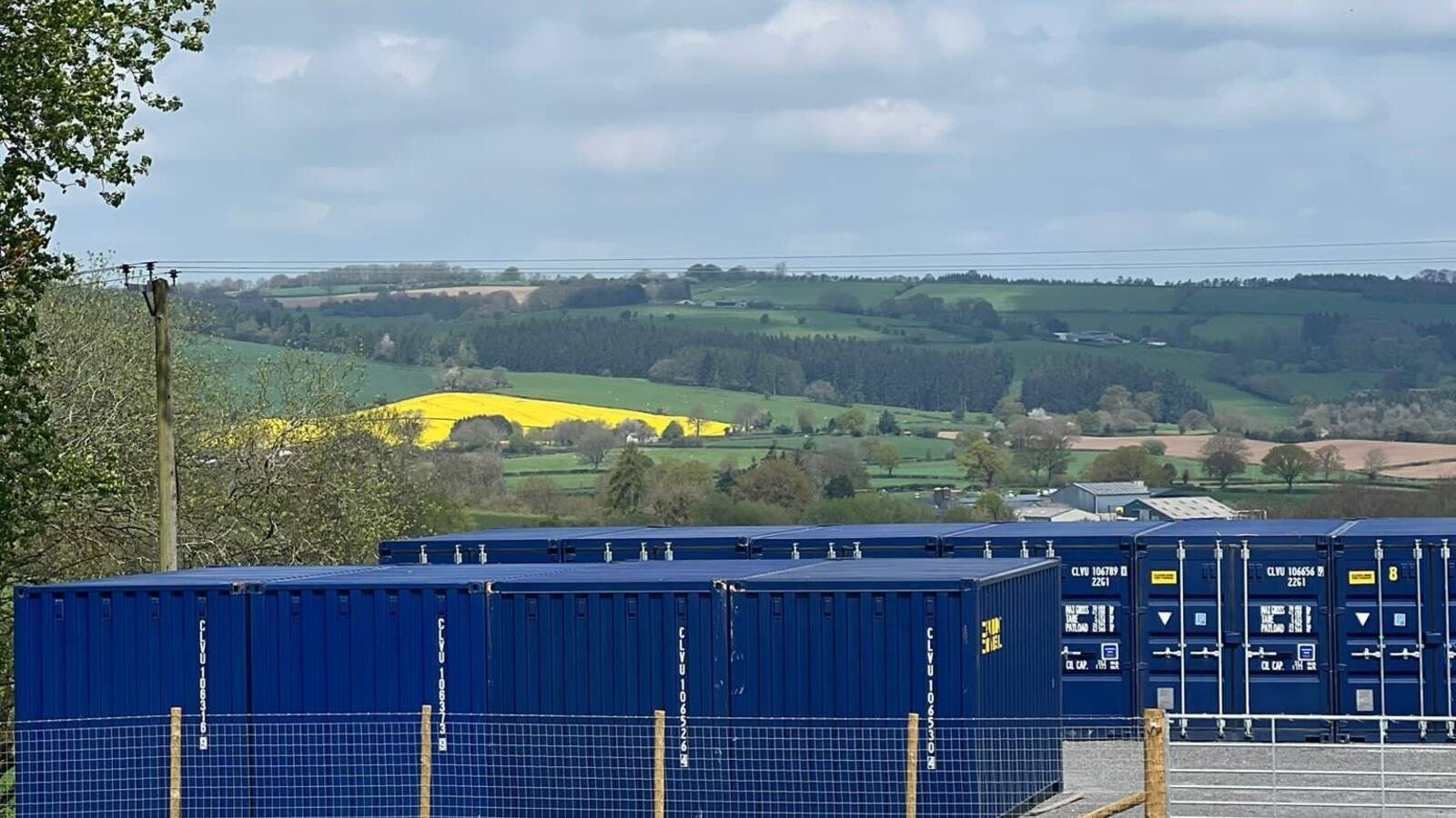 Rows of navy storage containers on the gravel yard at Penrhos Farm